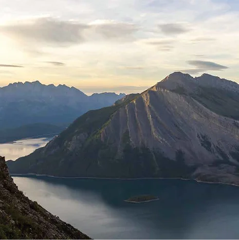 Norweski fiord z górskimi szczytami o zachodzie słońca.